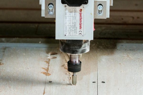 pexels-harold-granados-115813190-10119306 Maskin som utför CNC fräsning i verkstaden på träplankor